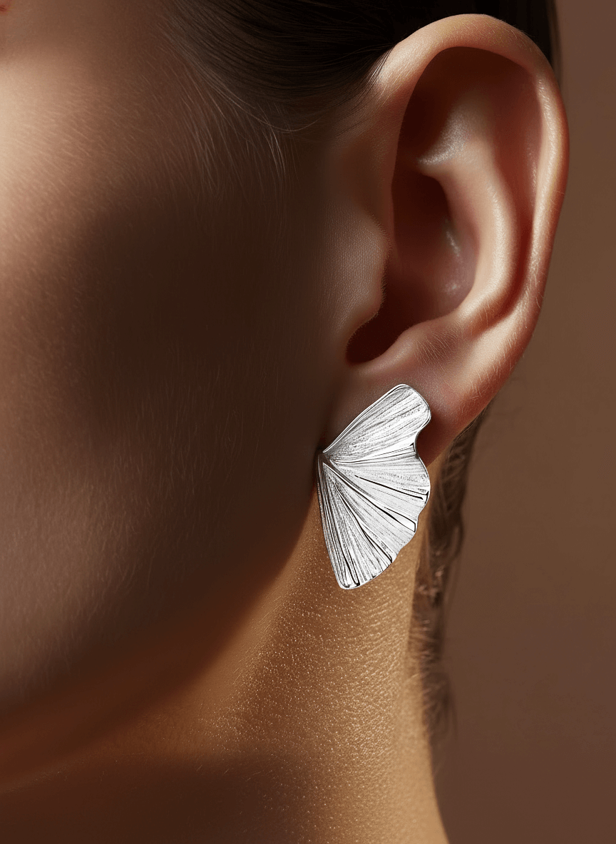 Silver butterfly earring worn by a person with a neutral background