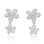Silver flower-shaped earrings with pearls on a white background