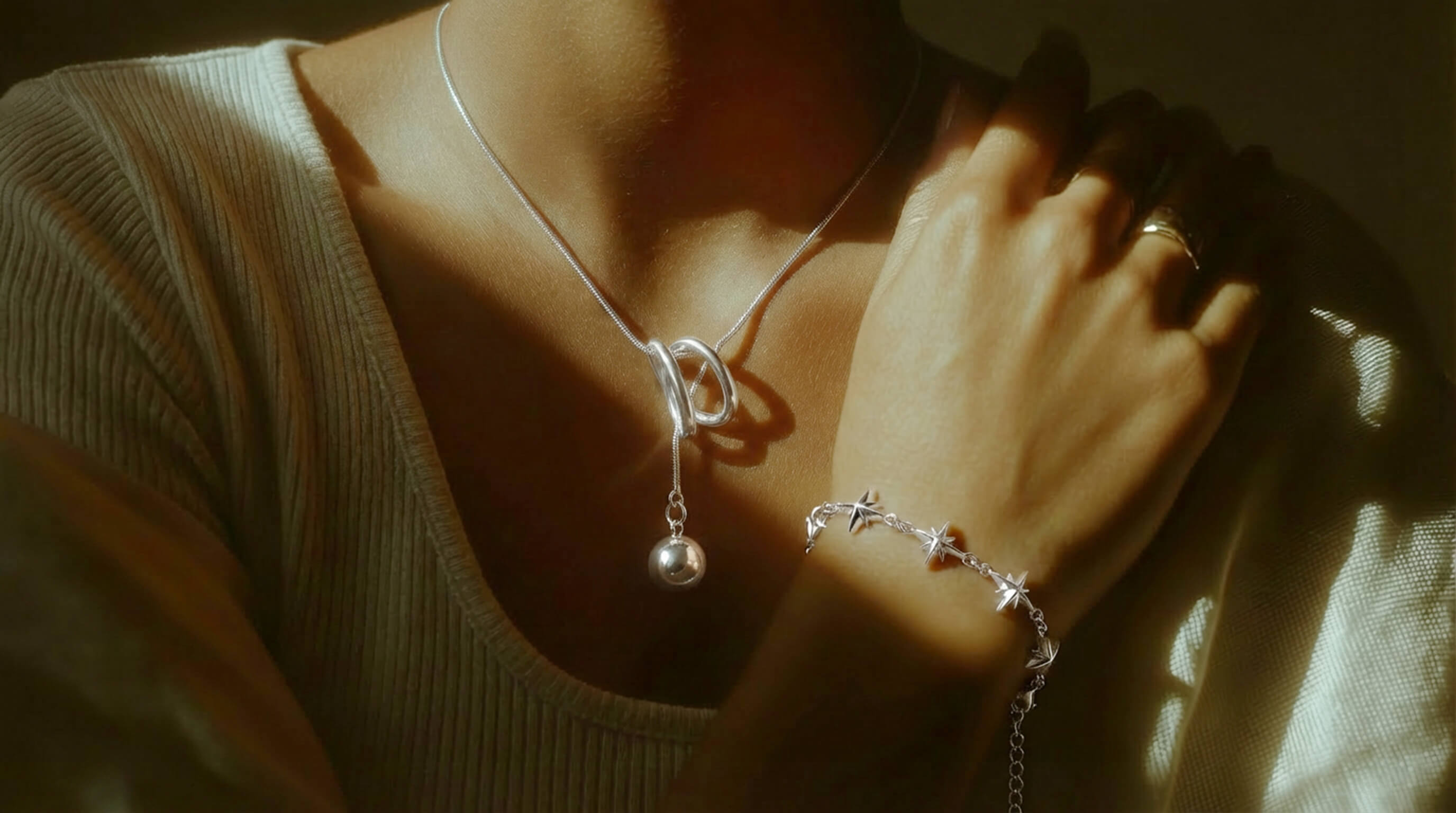 Close-up of a person wearing a necklace and bracelet with soft lighting